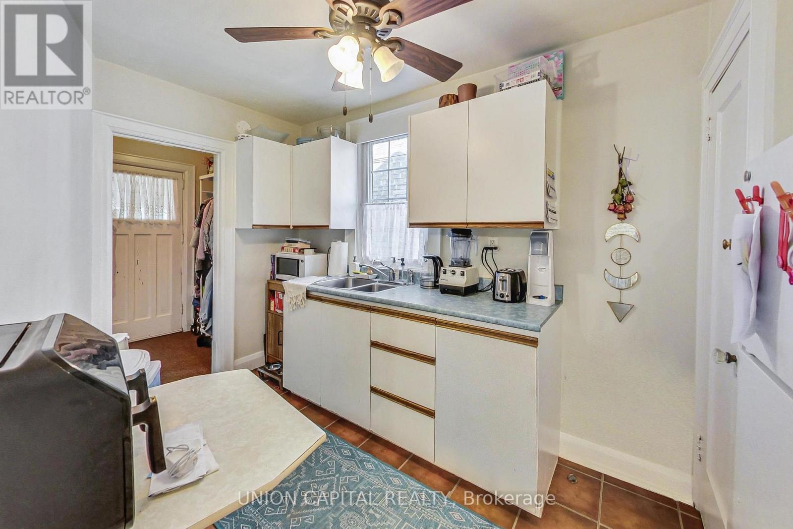 A kitchen with white cabinets and a ceiling fan.
