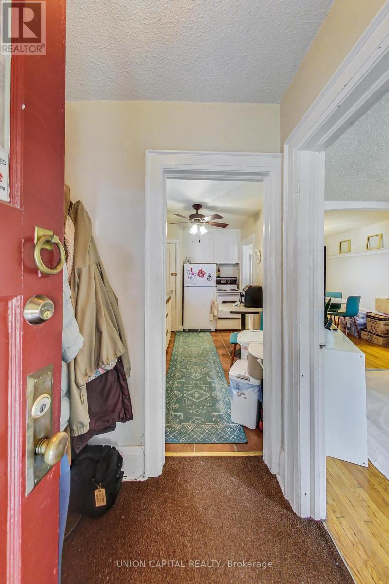 A hallway with a red door and a carpet leading to a bedroom.