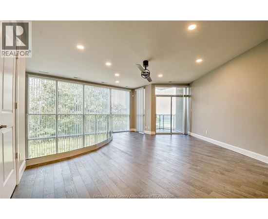 A spacious room with a sliding glass door leading to a balcony.
