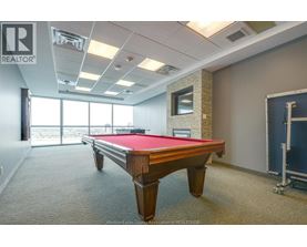 A pool table in a room with a window overlooking the ocean.