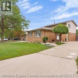 A house with a green lawn and a tree in front of it.