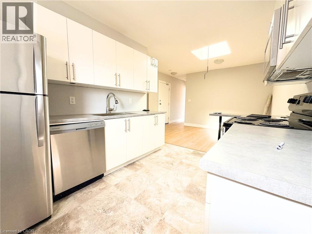 A kitchen with a refrigerator, stove, and cabinets.