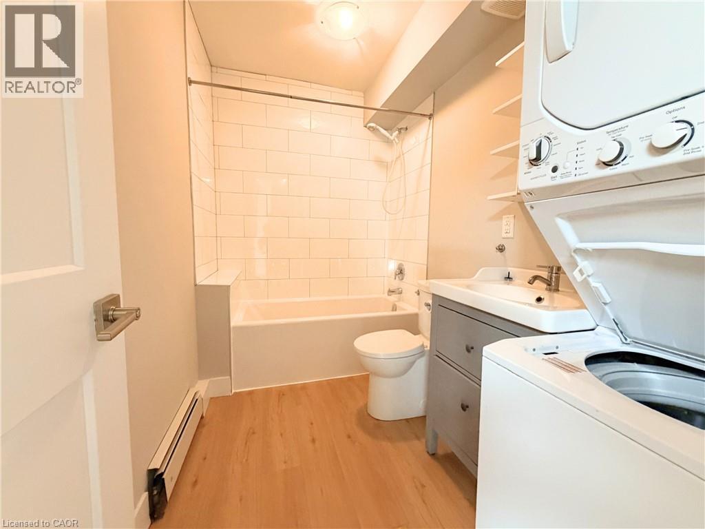 A small bathroom with a toilet, sink, and a washer and dryer.
