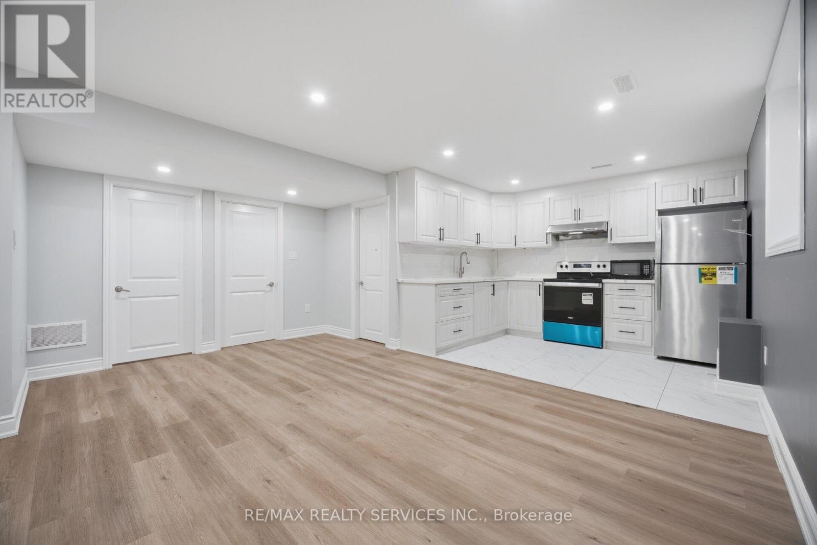 A spacious kitchen with wooden flooring and white cabinetry.