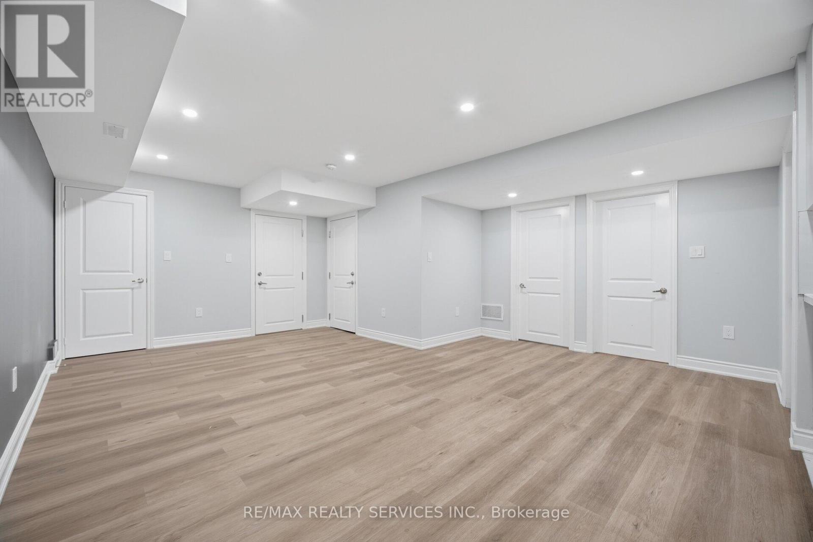 A spacious room with wooden flooring and white walls.