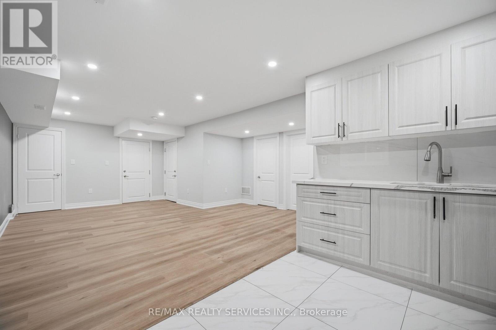 A spacious kitchen with white cabinets and a wooden floor.