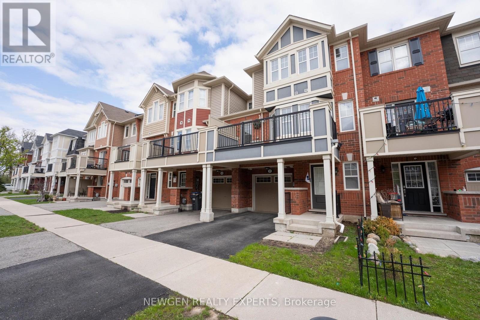 A row of townhouses with balconies and a sign that says Newgen Realty Experts Brokerage.