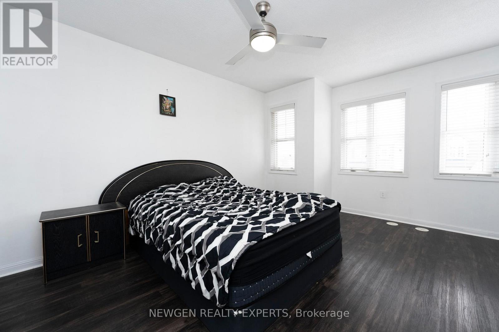 A bedroom with a black and white bedspread and a ceiling fan.