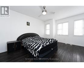 A bedroom with a black and white bedspread and a ceiling fan.