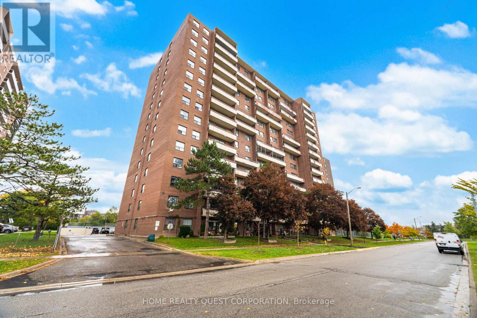 A tall brick building with a parking lot in front of it.