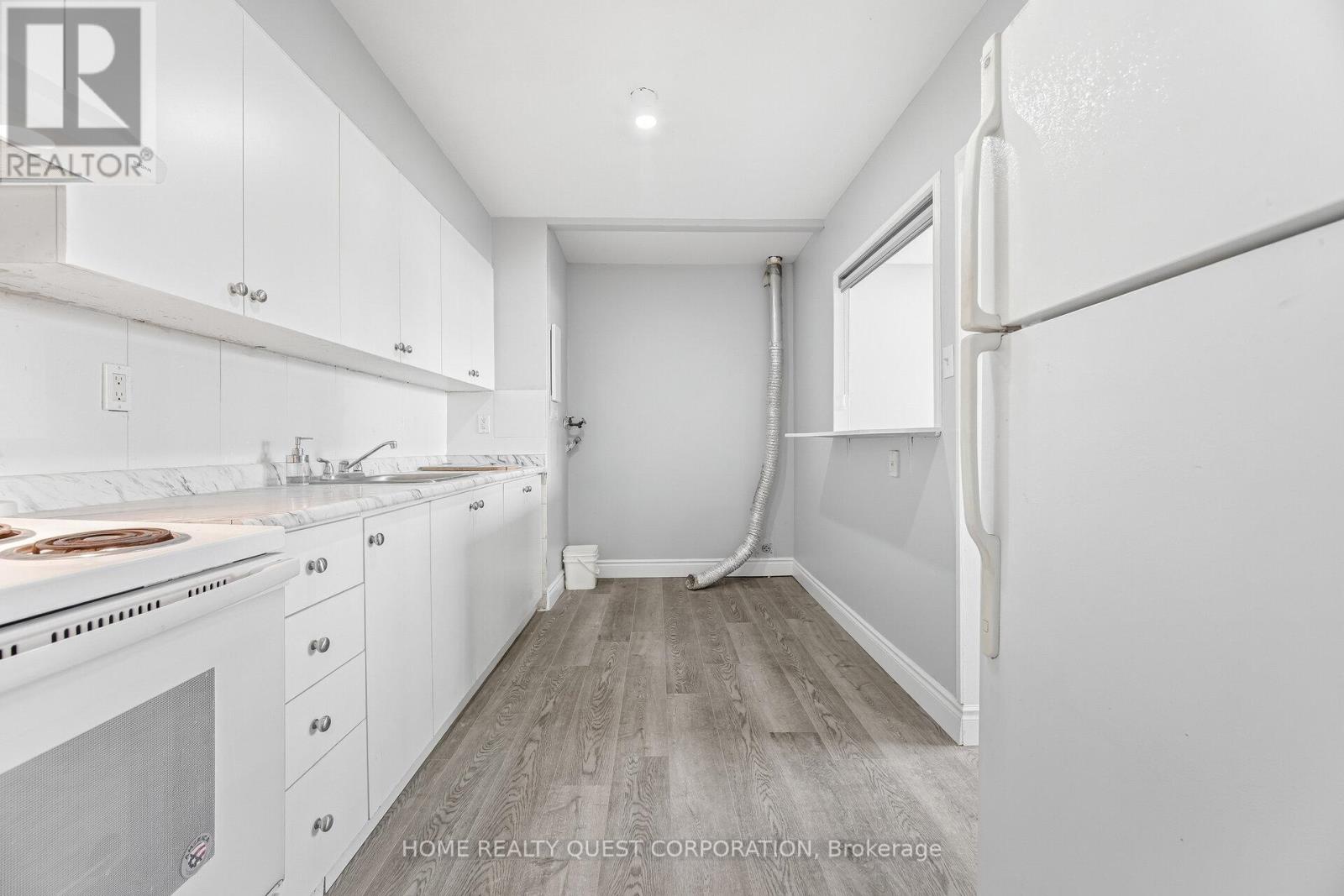 A white kitchen with wooden floors and white cabinets.
