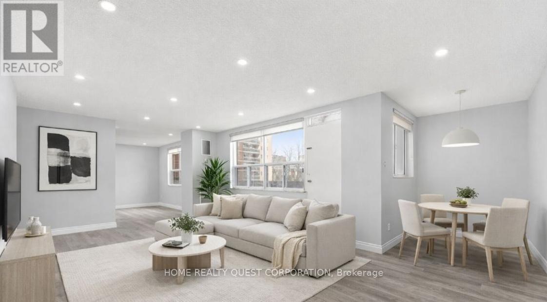 A well-lit, modern living room with a large sofa, a coffee table, and a dining table.