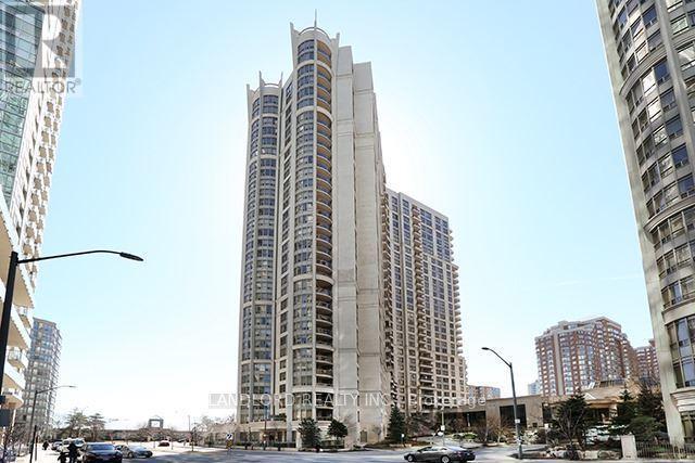 A tall building with many windows is in the middle of a city street.
