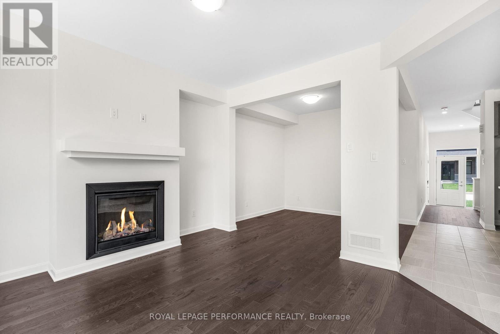 A spacious room with a fireplace and wooden floors.