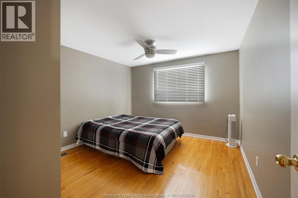 A bedroom with a bed, a ceiling fan, and a door.