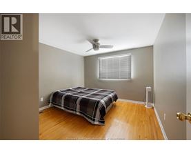 A bedroom with a bed, a ceiling fan, and a door.