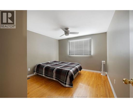 A bedroom with a bed, a ceiling fan, and a door.
