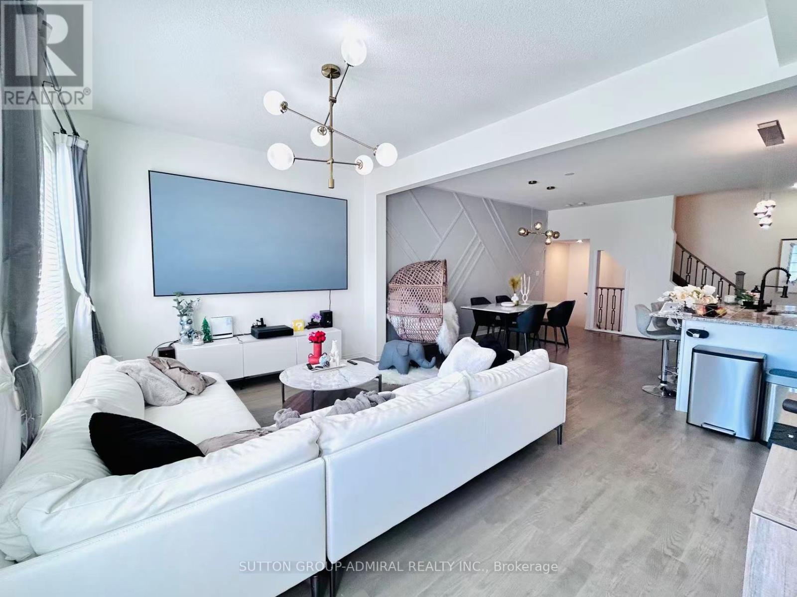 A living room with a white couch and a television mounted on the wall.