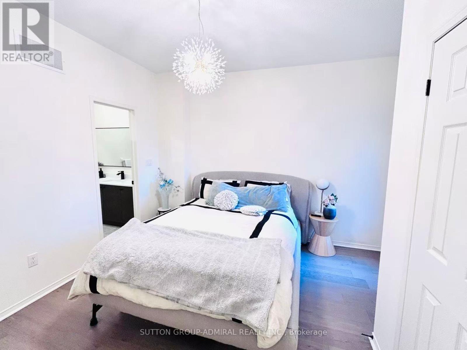 A bedroom with a bed, nightstand, and a chandelier.