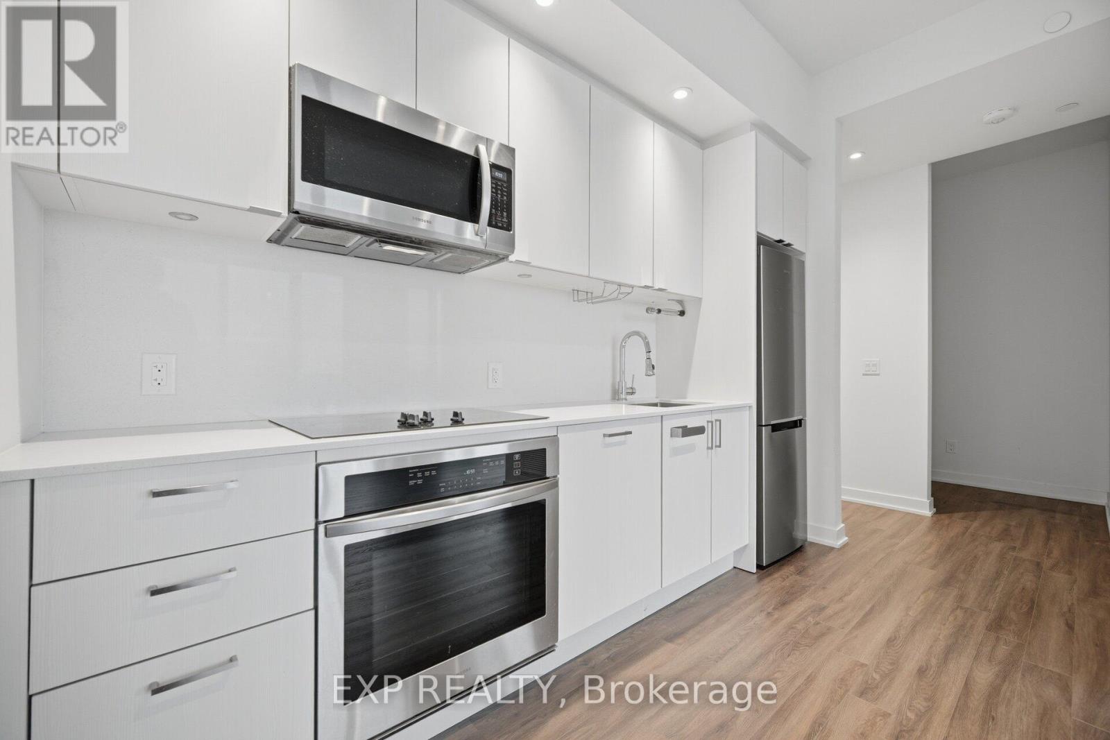 A modern kitchen with white cabinets and stainless steel appliances.