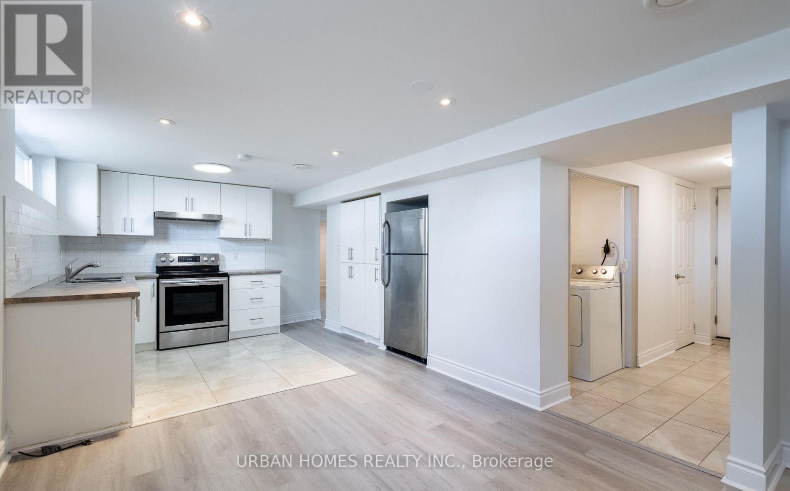 A spacious kitchen with white cabinets and a refrigerator.
