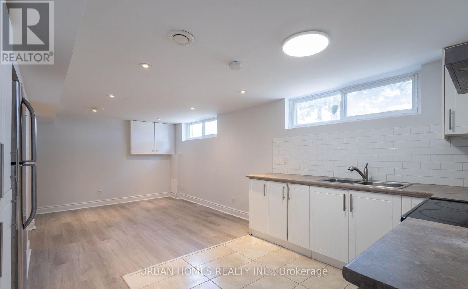 A kitchen with white cabinets and a wooden floor.