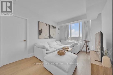 A living room with a white couch and a painting on the wall.