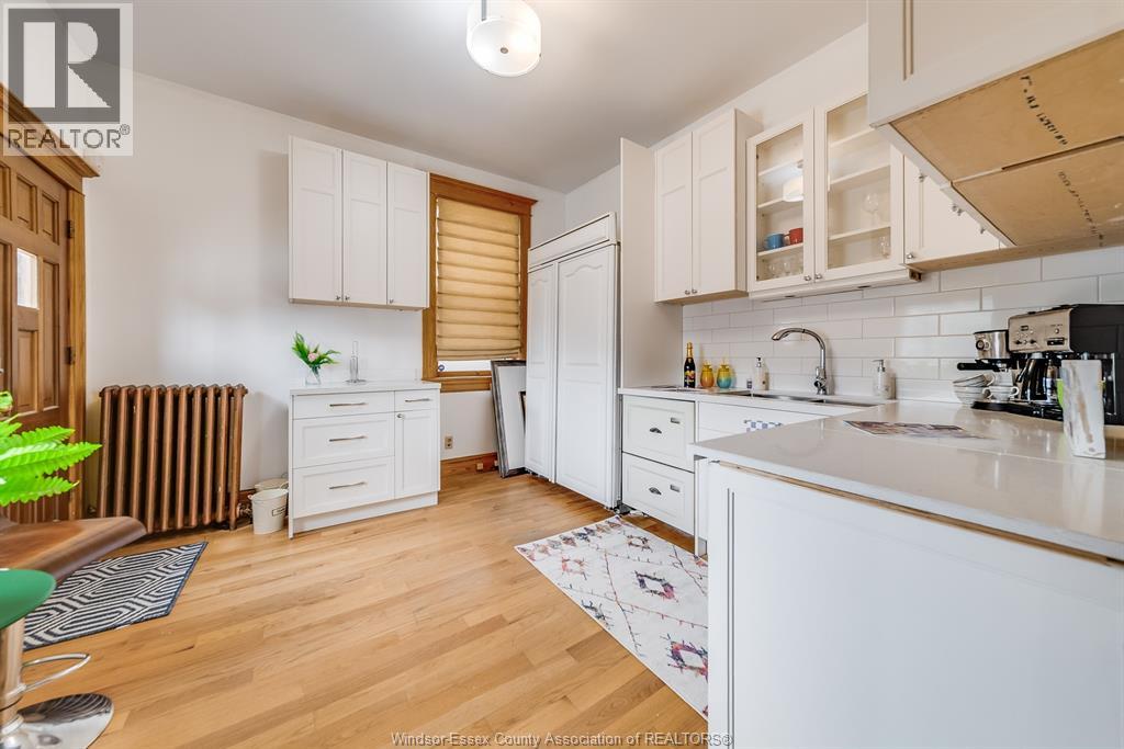 A kitchen with white cabinets and a wooden floor.