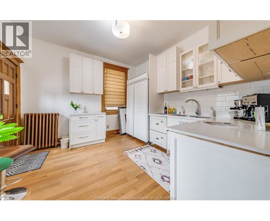 A kitchen with white cabinets and a wooden floor.