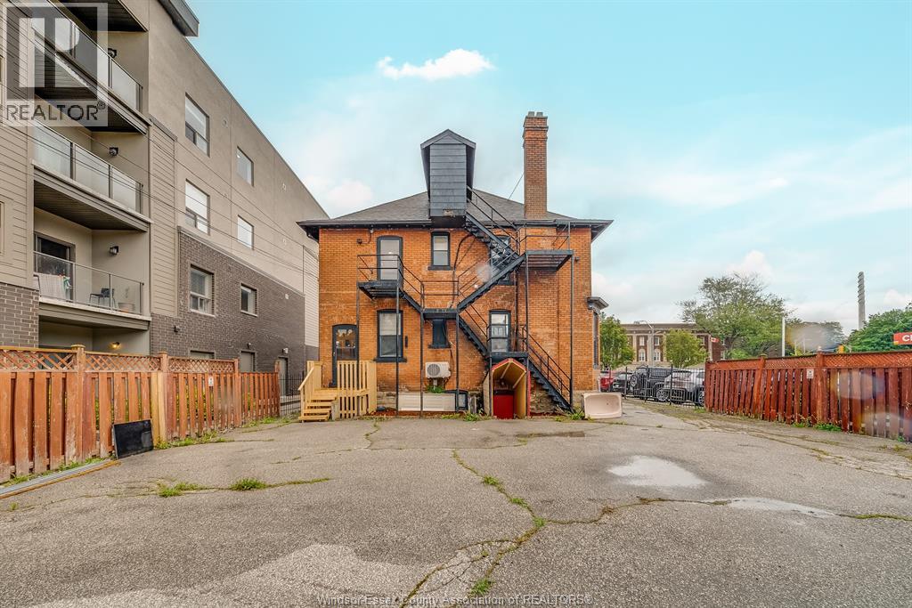 A brick house with a chimney is in the foreground with apartment buildings in the background.