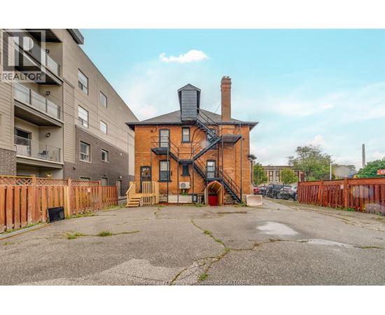 A brick house with a chimney is in the foreground with apartment buildings in the background.