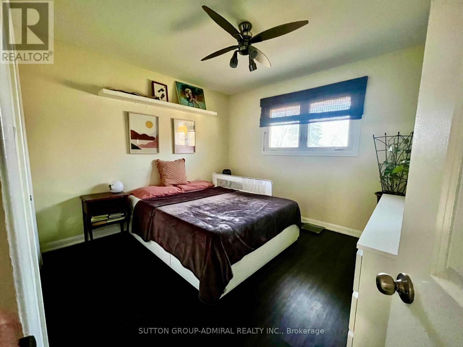 A bedroom with a bed, nightstand, and a ceiling fan.