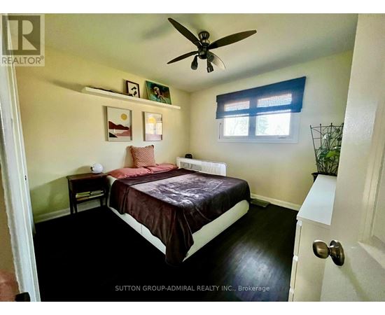 A bedroom with a bed, nightstand, and a ceiling fan.