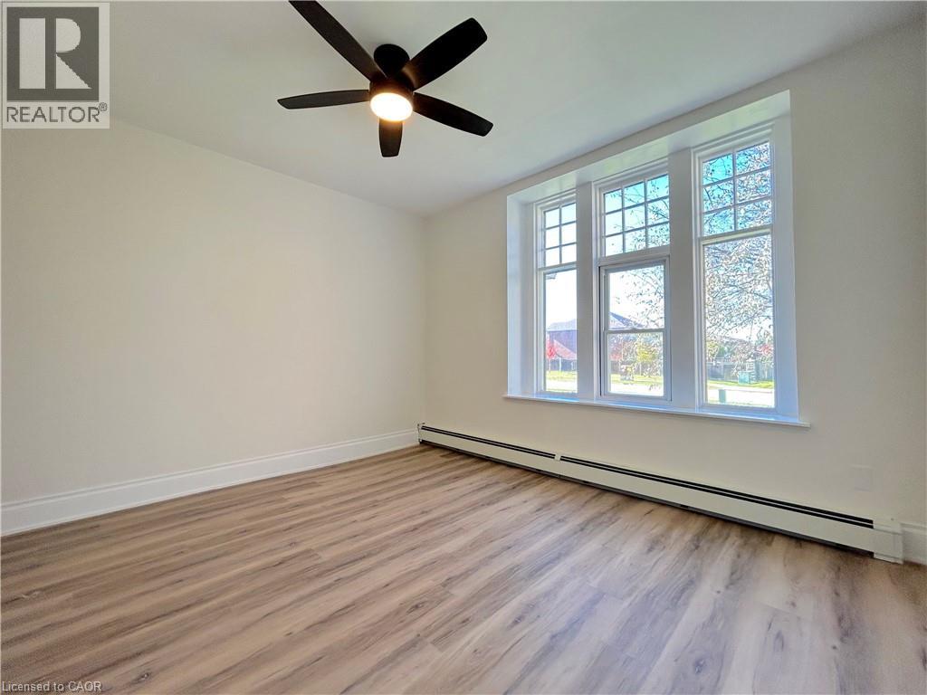 A room with a ceiling fan and a window with a view of trees.