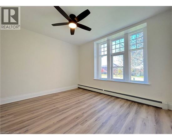 A room with a ceiling fan and a window with a view of trees.