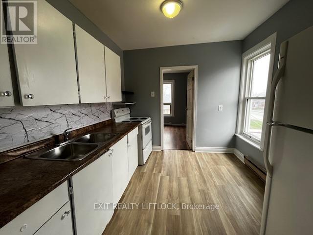 A kitchen with white cabinets and a wooden floor.