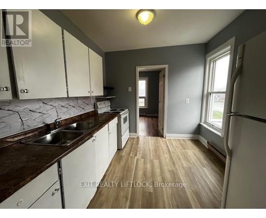 A kitchen with white cabinets and a wooden floor.