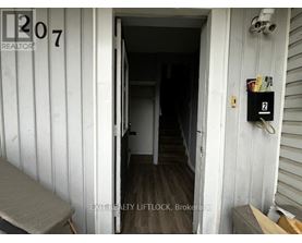 A white door with a number 207 on it and a sign that says REALTOR.