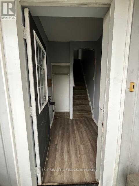 A hallway with a door on the left and a staircase on the right.