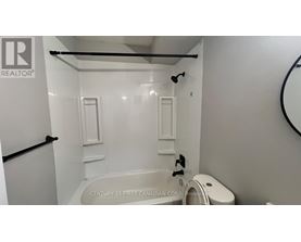 A white bathroom with a tub and toilet.