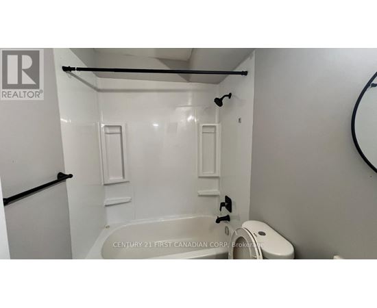 A white bathroom with a tub and toilet.