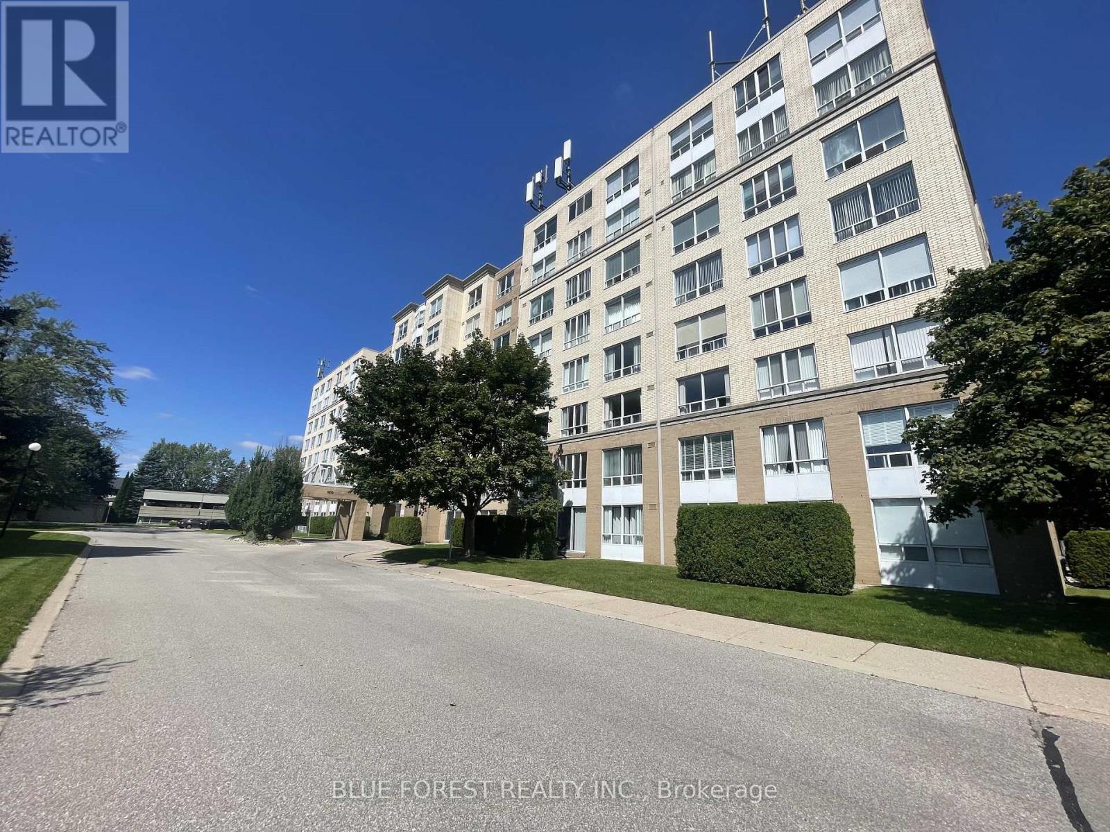 A street view of a residential building with a brokerage logo on the top left.