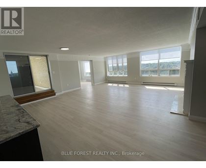 A spacious room with wooden flooring and large windows.