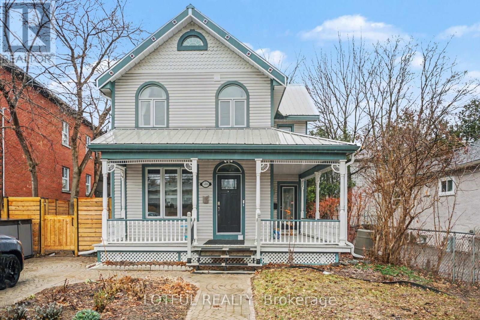 A house with a green roof and a porch with white railings.