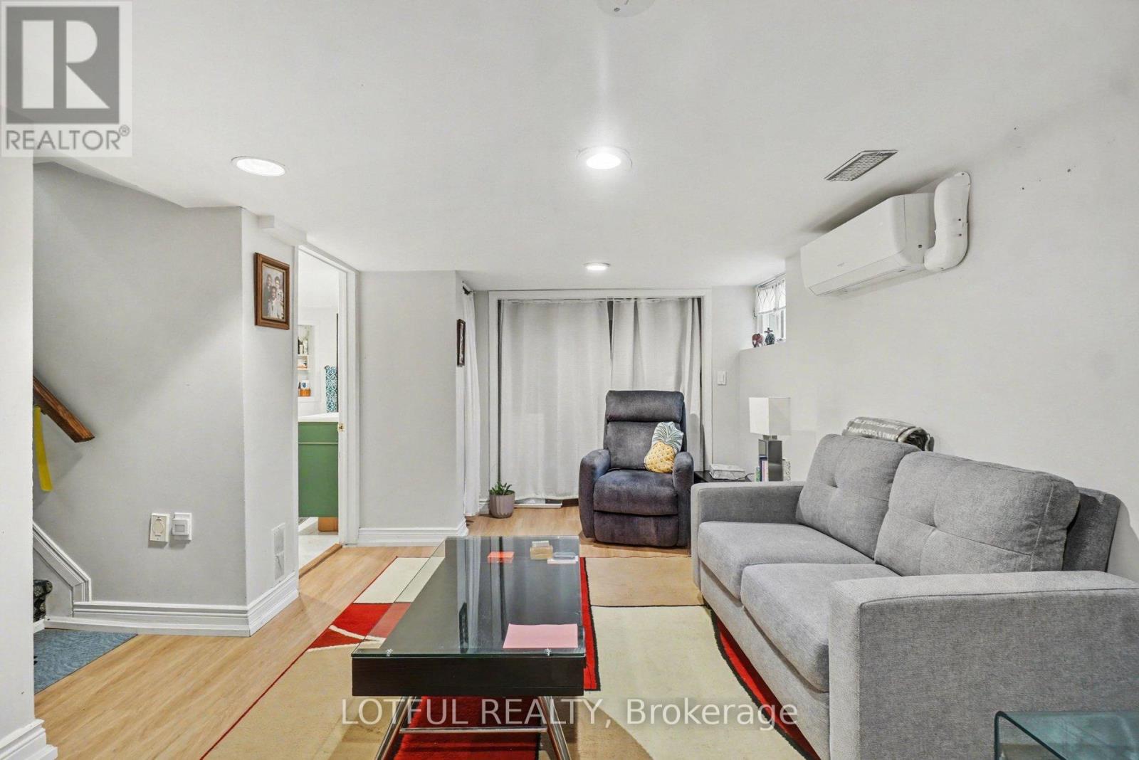 A living room with a grey couch and a red rug.