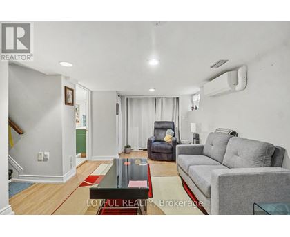 A living room with a grey couch and a red rug.