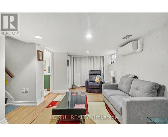 A living room with a grey couch and a red rug.