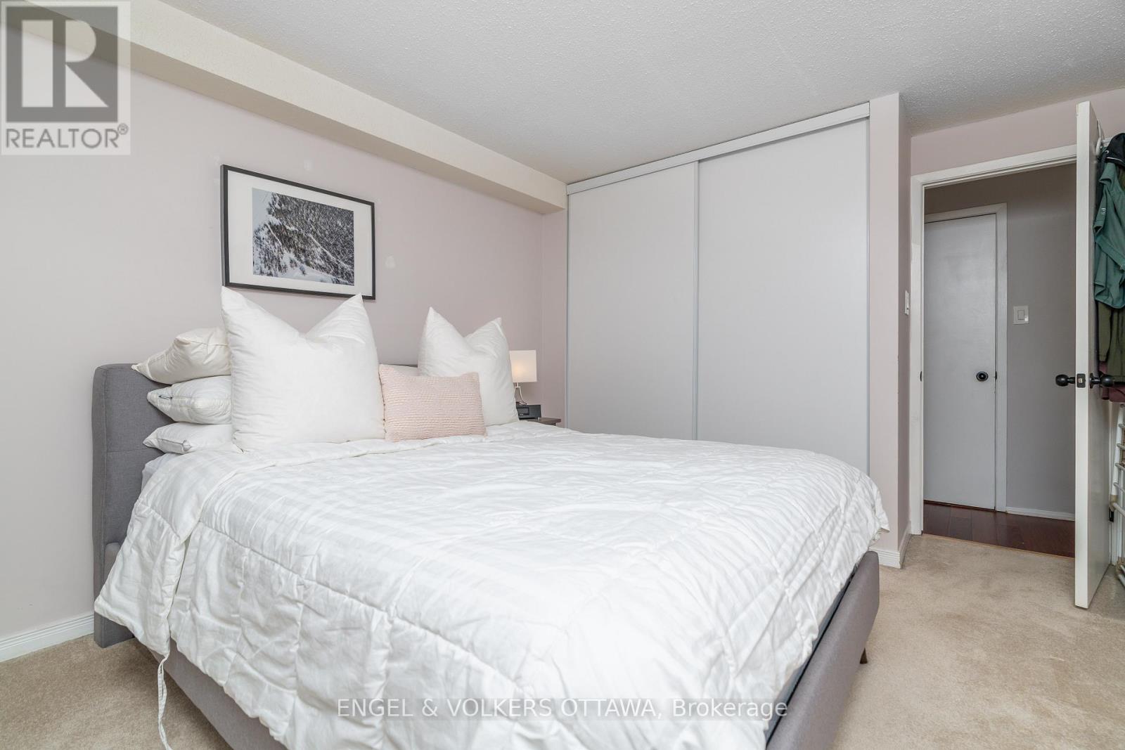 A bedroom with a white bed and a grey headboard.