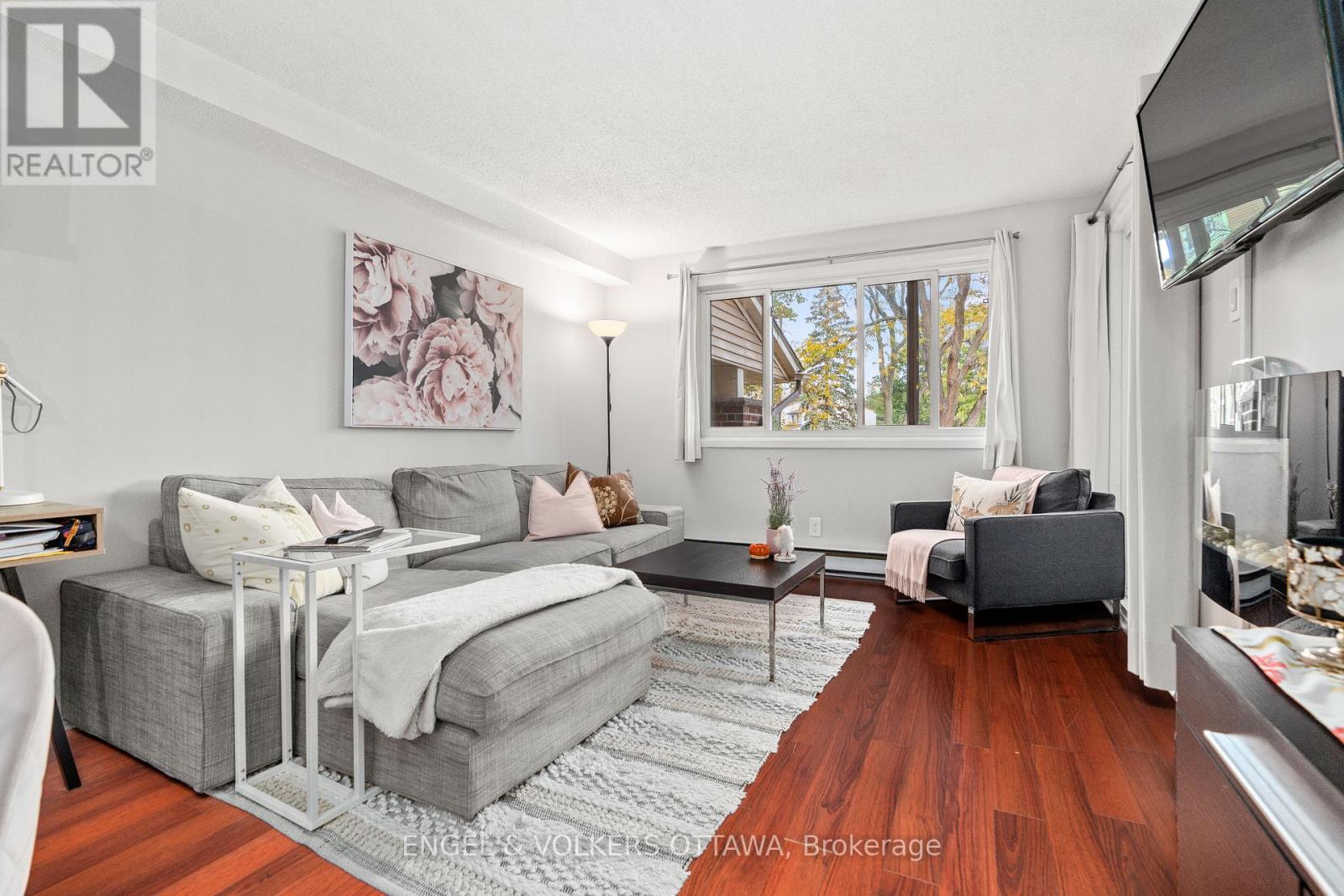 A living room with a grey couch and a wooden floor.