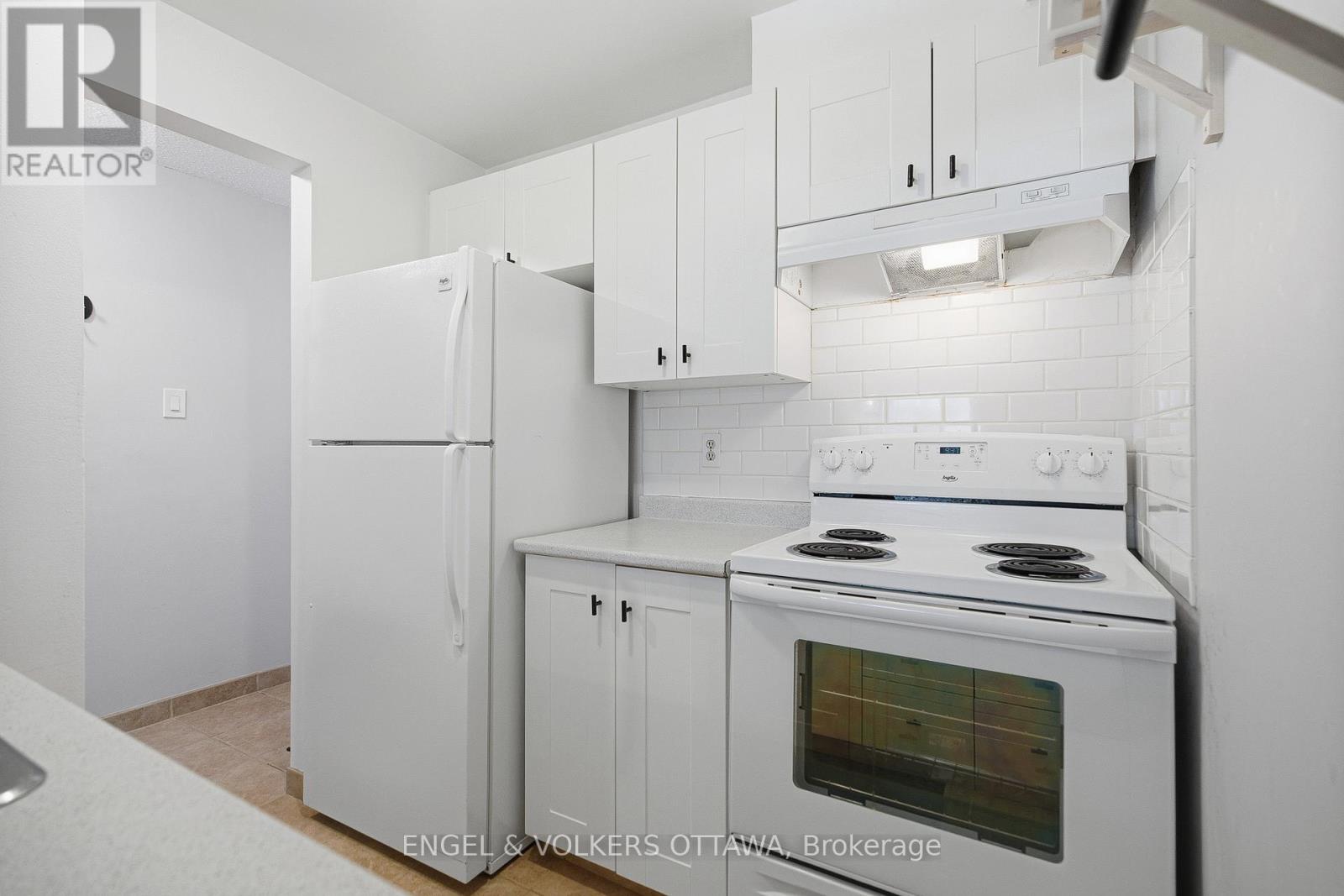 A white kitchen with a stove and a refrigerator.